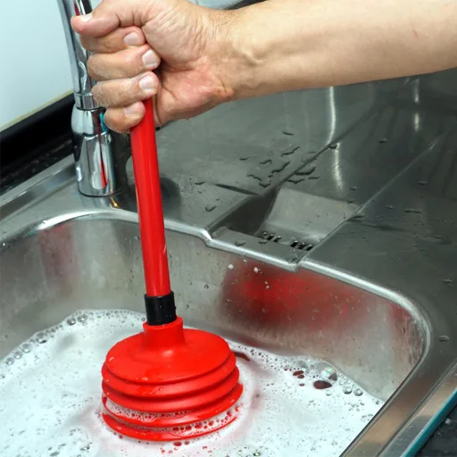 Desentupimento de pia com desentupidor manual em uma cozinha.